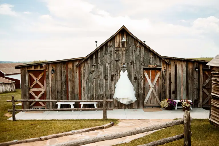 The weathered wood Bride Barn at Younger Ranch with a wedding dress hanging out front