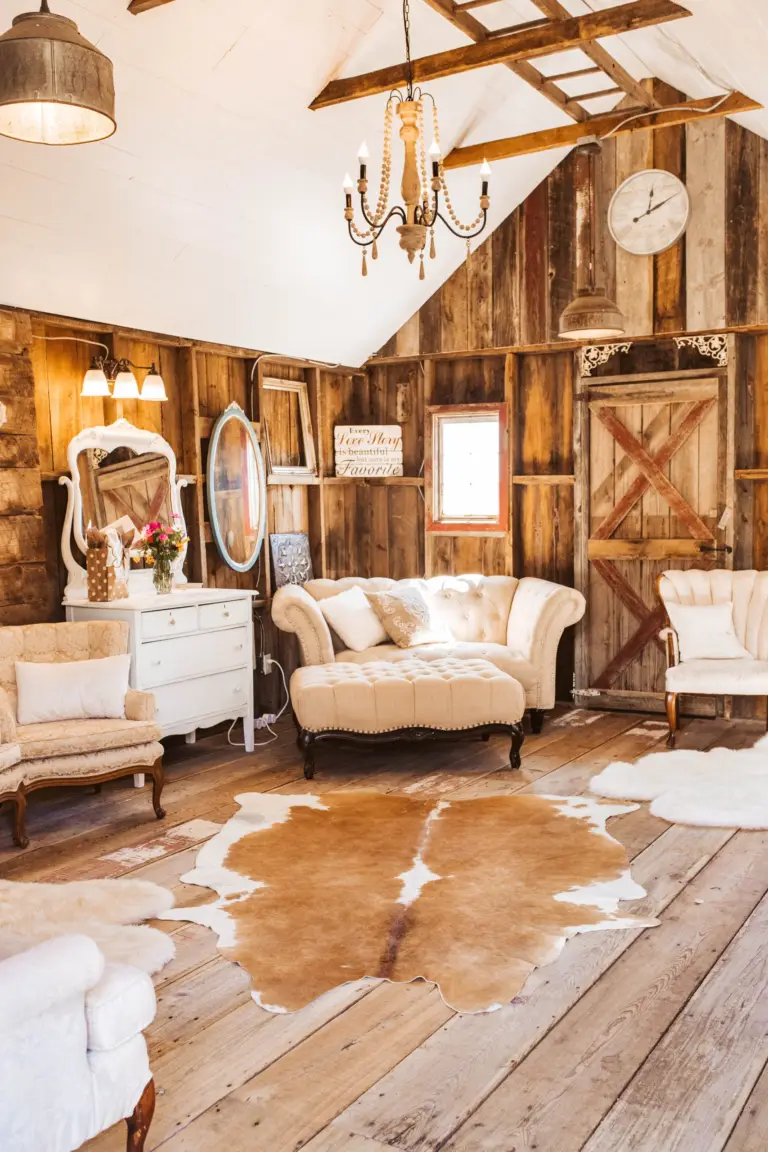Inside the Bride Barn: antique furniture, a cowhide rug, vanity mirrors, and a white shiplap ceiling with a chandelier