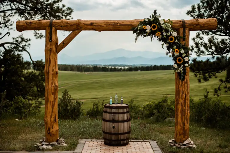 Hand-peeled ponderosa pine ceremony arch at Younger Ranch with Pikes Peak on the horizon