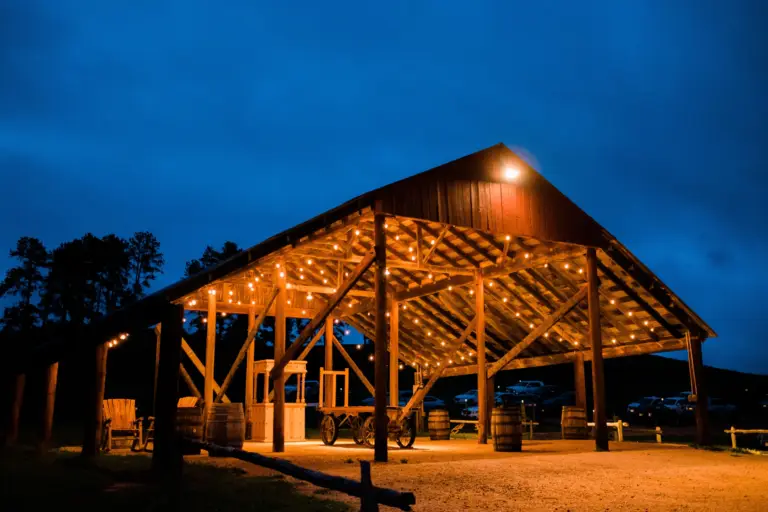 The open-air cocktail barn at Younger Ranch glowing with market lights at dusk