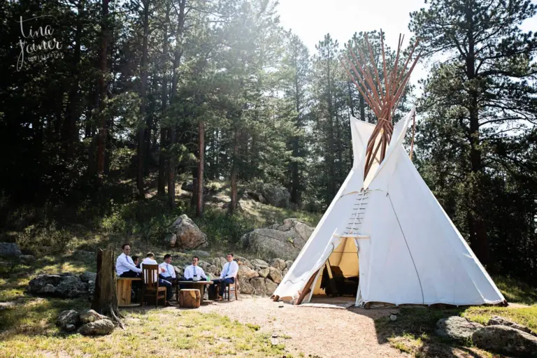 The 25-foot Groom’s Tipi among the pines at Younger Ranch with the groomsmen relaxing outside